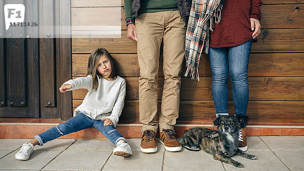 Mädchen mit Eltern und Hund an der Holzwand gestikulierend