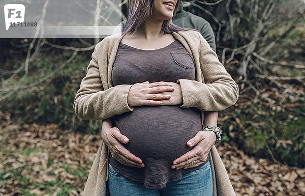 Mann mit dem Bauch einer schwangeren Frau in der Natur