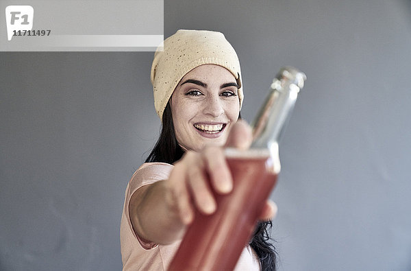 Porträt einer lächelnden jungen Frau mit Flasche