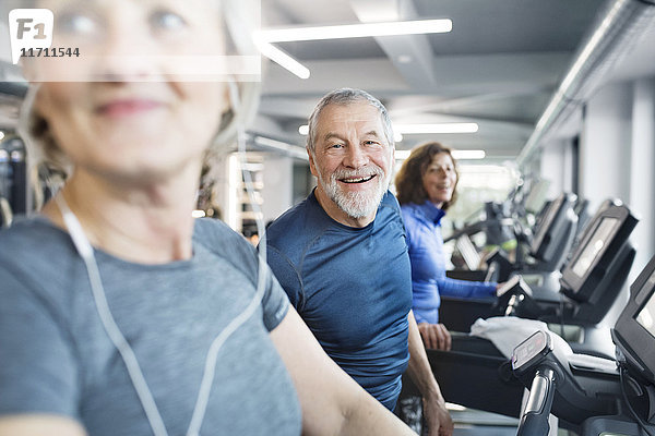 Gruppe von fit Senioren auf Laufbändern im Fitnessstudio  Mann lächelt