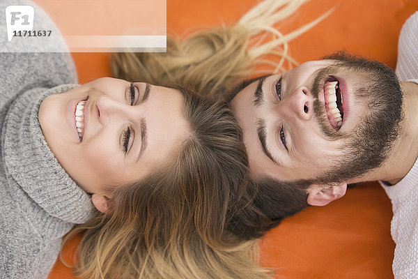 Porträt eines lachenden Paares Kopf an Kopf auf Decke liegend