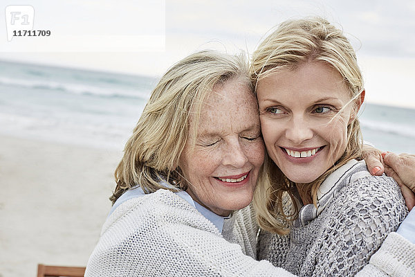 Mutter und Tochter umarmen sich am Strand