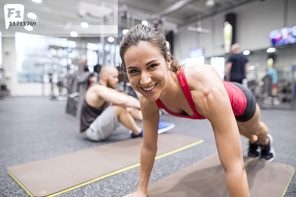 Porträt einer lächelnden jungen Frau beim Training im Fitnessstudio
