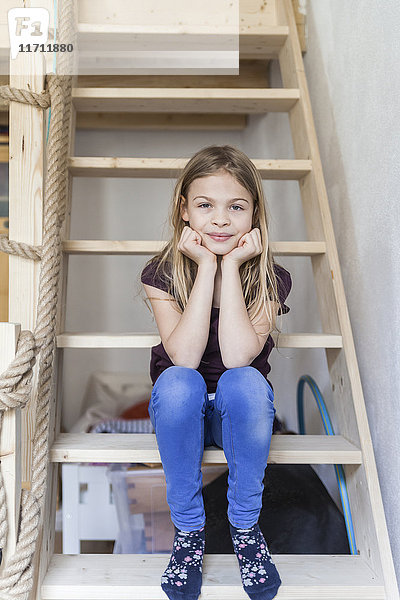 Porträt eines Mädchens  das auf der Leiter ihres Hochbettes sitzt.
