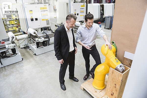 Zwei Männer reden in der Fabrikhalle am Industrieroboter