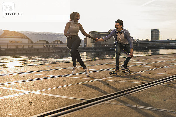 Junges Paar beim Skateboarden am Flussufer