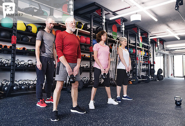 Gruppe von fitten Senioren mit Personal Trainer im Fitnessstudio