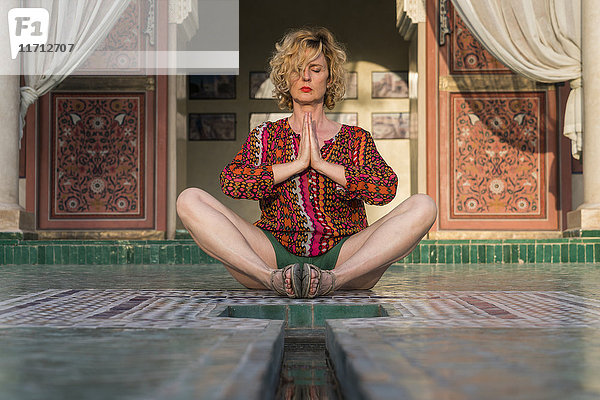 Marokko  Marrakesch  Tourist auf dem Boden sitzend beim Yoga
