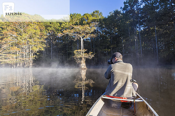 USA  Texas  Louisiana  Caddo Lake  kahler Zypressenwald  Tourist mit Kamera im Kajak