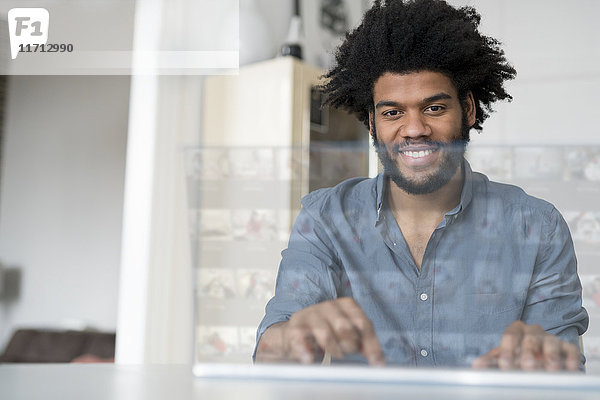 Lächelnder Mann zu Hause bei der Arbeit am futuristischen Bildschirm
