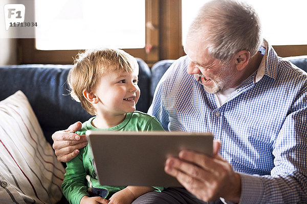 Großvater und Enkel auf der Couch sitzend  mit digitalem Tablett