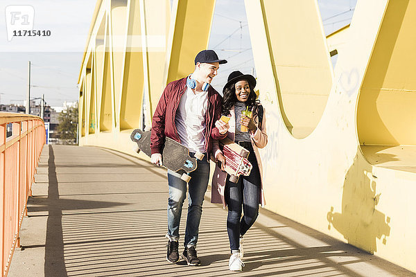 Junges Paar mit Skateboard auf der Brücke