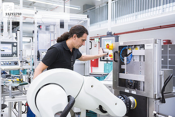 Mann mit Montageroboter in der Fabrik