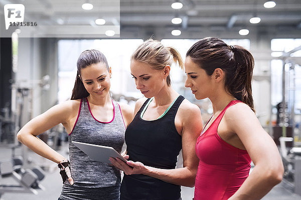 Drei Frauen mit Tablette nach dem Training im Fitnessstudio