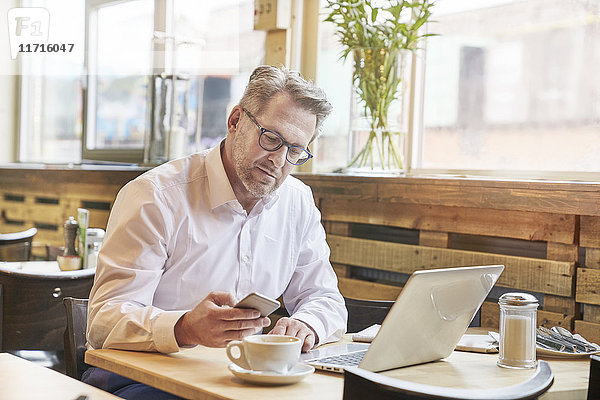 Reife Geschäftsleute im Cafe mit Laptop und Handy
