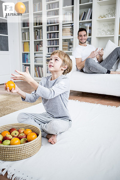 Junge jongliert mit Orangen zu Hause