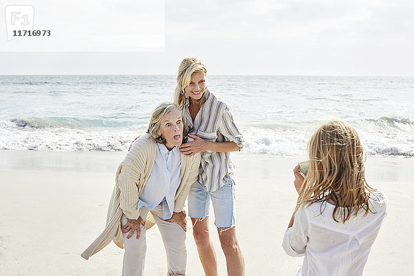 Kleines Mädchen beim Fotografieren am Strand ihrer Mutter und Großmutter