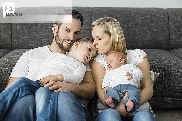 Eltern mit männlichem Neugeborenen und kleinem Sohn  die sich zu Hause entspannen.