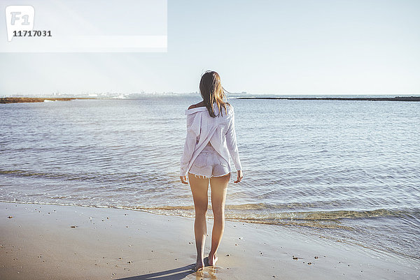 Rückansicht der Frau am Strand mit Blick aufs Meer