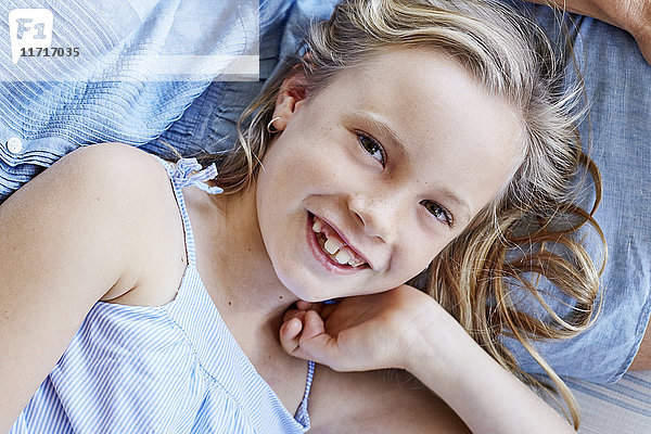 Porträt eines lächelnden kleinen Mädchens mit Zahnlücke auf dem Schoß der Mutter.