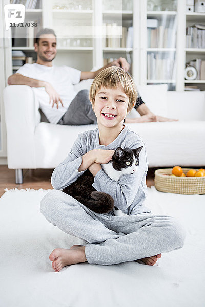 Lächelnder Junge streichelt Katze zu Hause