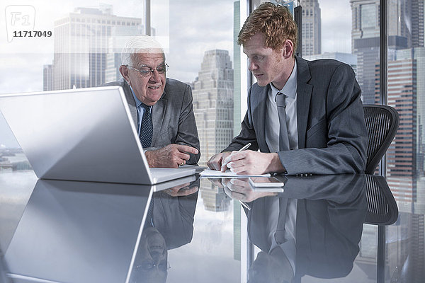 Zwei Geschäftsleute mit Laptop diskutieren im Büro