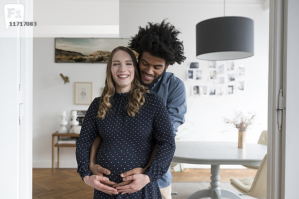 Lächelndes schwangeres Paar im Wohnzimmer