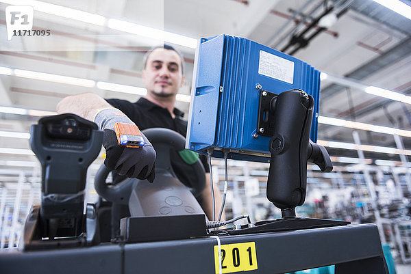 Mann mit tragbarem Scanner am Schlepperzug in der Fabrikhalle