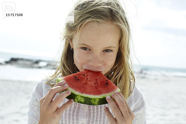 Kleines Mädchen isst Wassermelone am Strand
