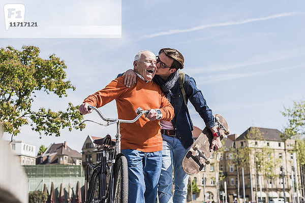 Erwachsener Enkel küsst glücklichen älteren Mann in der Stadt