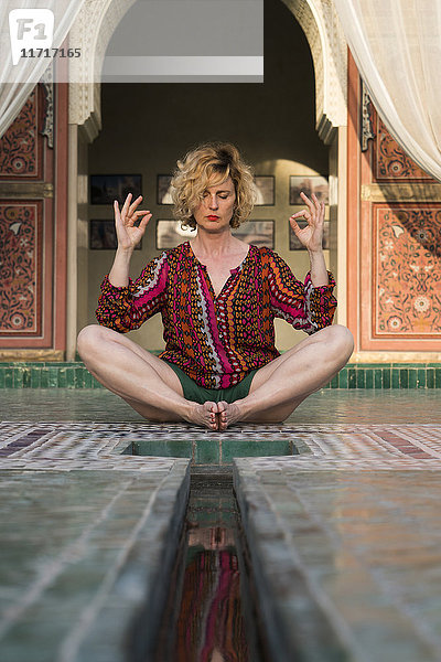 Marokko  Marrakesch  Tourist auf dem Boden sitzend beim Yoga
