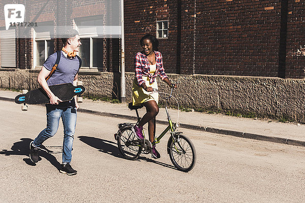Junges Ehepaar mit Fahrrad und Skateboard auf der Straße