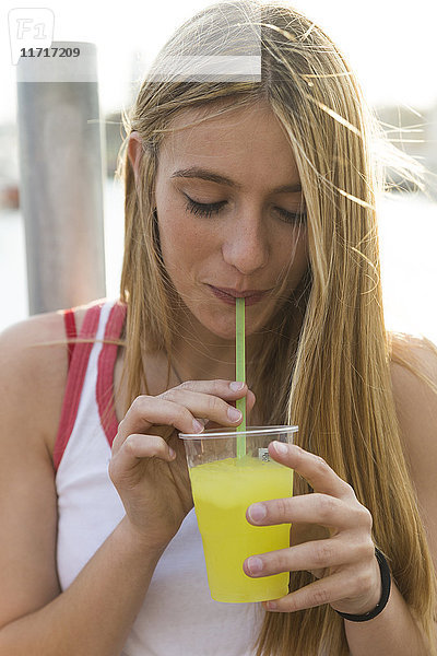 Junge Frau trinkt gelbes Getränk