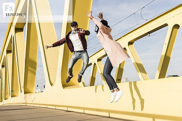 Glückliches Paar beim Springen auf der Brücke