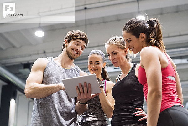 Gruppe von glücklichen Athleten mit Tablette nach dem Training im Fitnessstudio