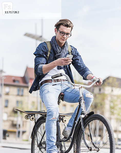 Junger Mann mit Fahrrad in der Stadt per Handy