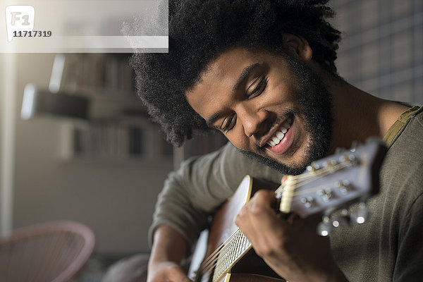 Lächelnder Mann beim Gitarrespielen