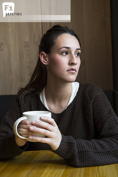 Porträt einer ernsten Frau mit einer Tasse Kaffee im Coffee Shop