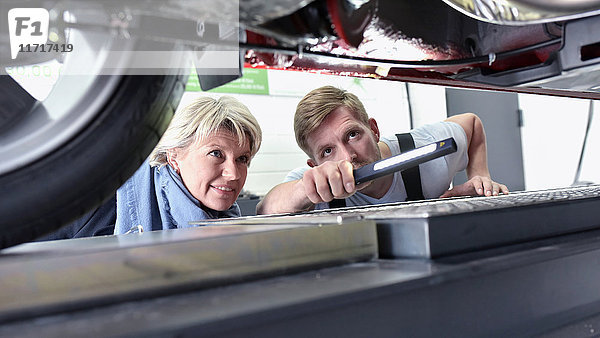 Kfz-Mechaniker mit Kunde in der Werkstatt am Auto