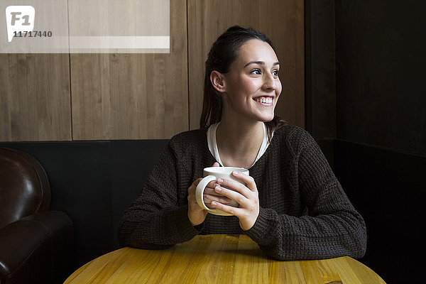 Porträt einer lächelnden Frau mit einer Tasse Kaffee im Coffee Shop