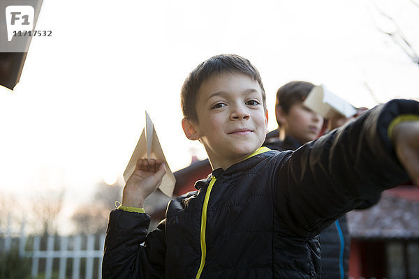 Portrait eines lächelnden Jungen mit Papierflugzeug