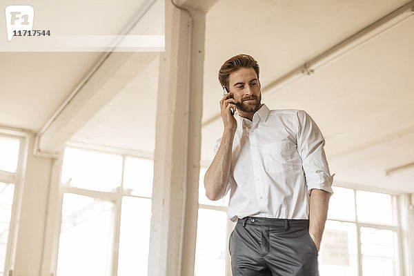Porträt eines jungen Geschäftsmannes am Telefon in einem Loft