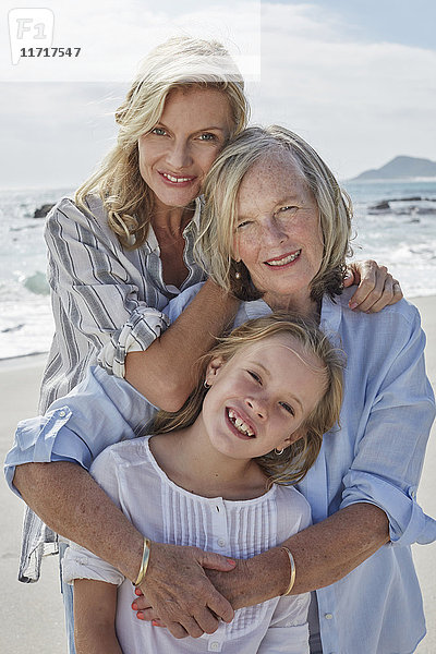 Mutter  Tochter und Großmutter am Strand umarmend