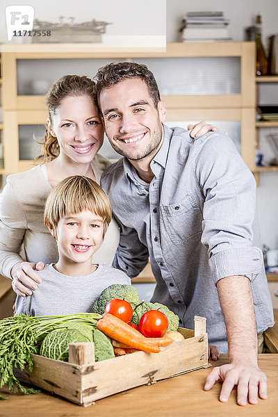 Lächelnde Familie mit Gemüsekiste in der Küche