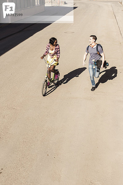 Glückliches Paar beim Laufen und Radfahren auf der Straße