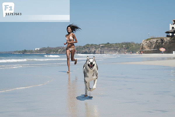 Mexiko  Riviera Nayarit Strand  junge Frau läuft mit Husky-Hund