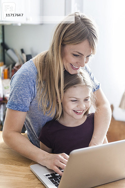 Mutter und Tochter mit Laptop in der Küche