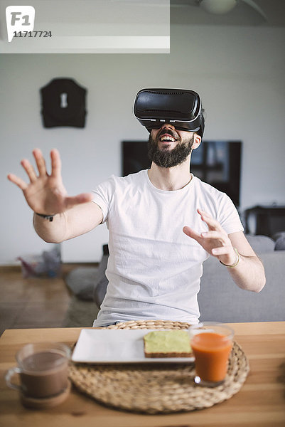 Mann beim Frühstück mit Virtual-Reality-Brille