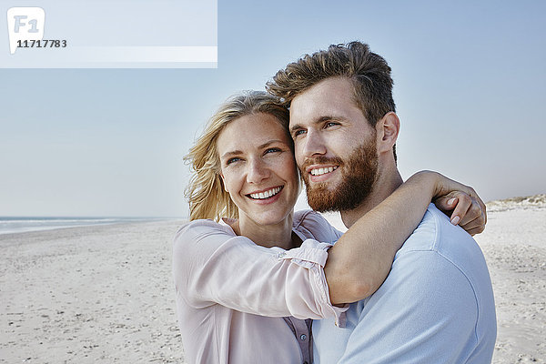 Ein glückliches Paar umarmt sich am Strand.