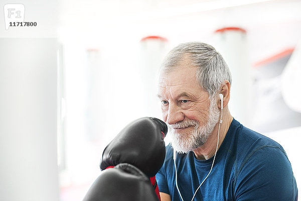 Fit Senior Mann mit Kopfhörern und Boxhandschuhen in der Turnhalle
